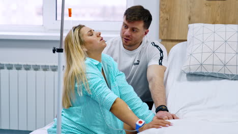 future mother is suffering from pain during contractions. man sitting beside supports her.