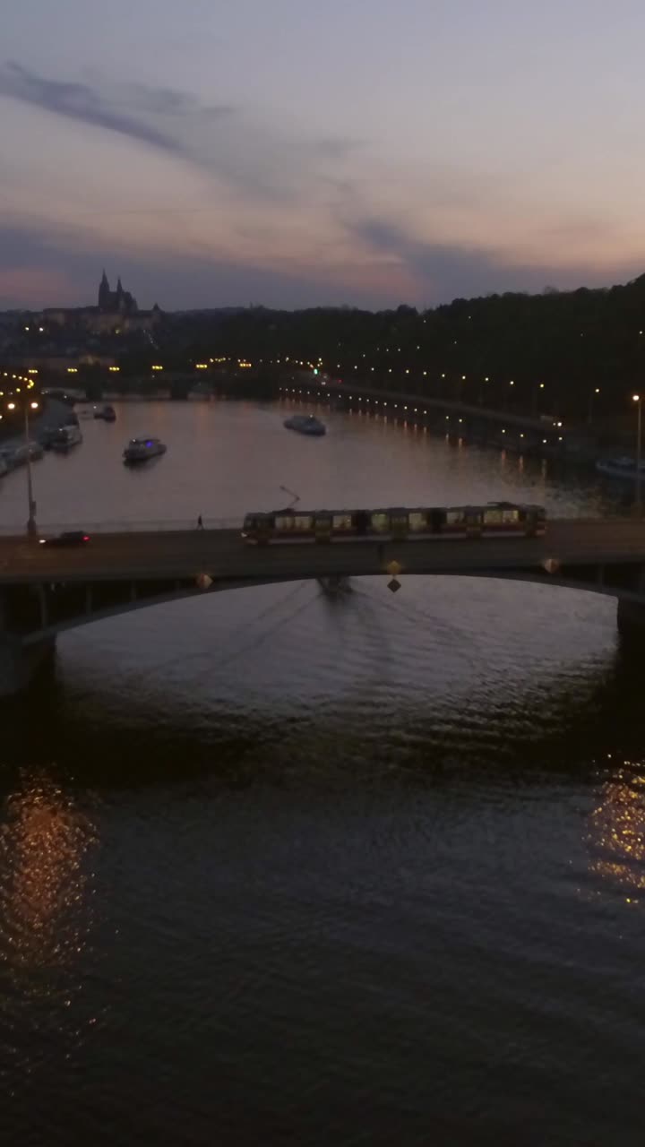 Paesaggio urbano di Praga al crepuscolo con fiume, ponte e barche.