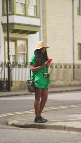 vertical video of female tourist on vacation in oxford uk exploring city walking along holywell street posing for selfie on mobile phone