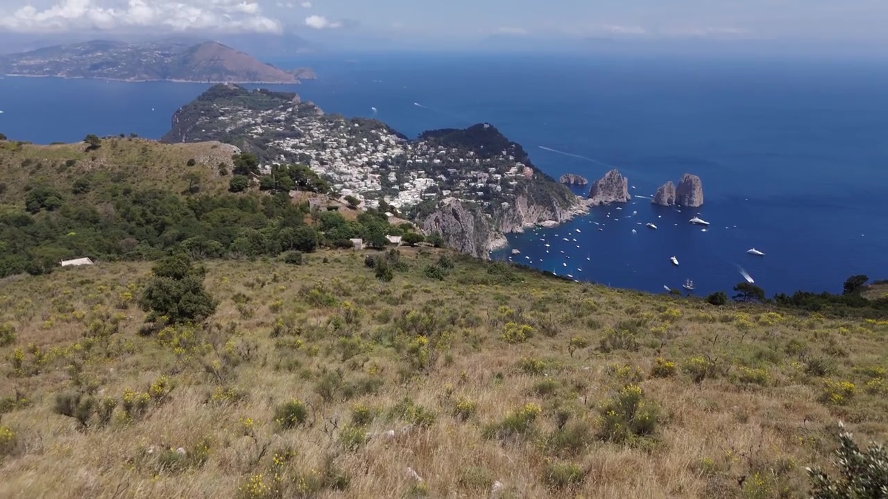 Toma de establecimiento con dron de la Isla de Capri, mientras un hombre camina hacia un árbol