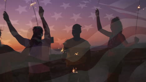 animation of flag of america over happy diverse friends dancing with sparklers on sunset beach