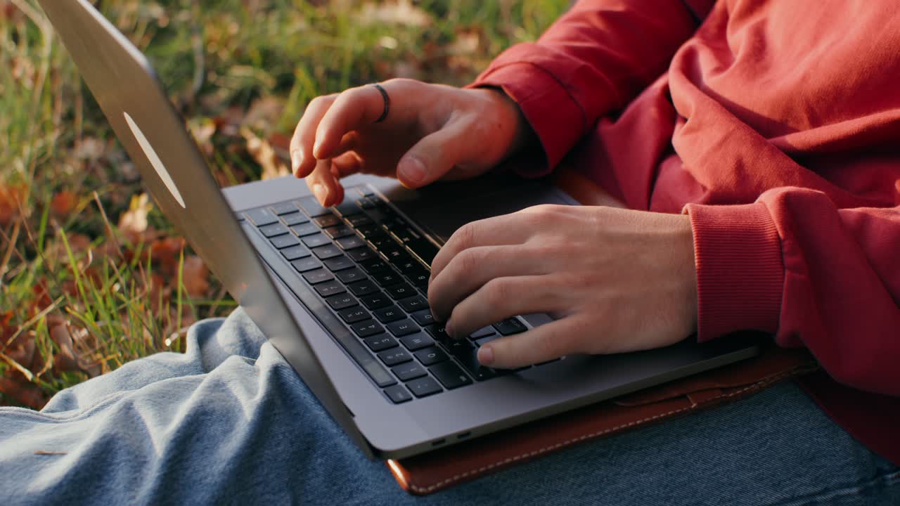 Person working on a laptop outdoors in autumn