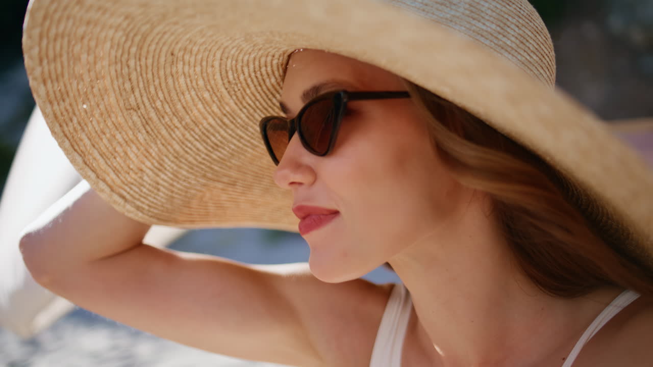 Closeup woman straw hat looking ahead at ocean horizon sitting at sun lounger
