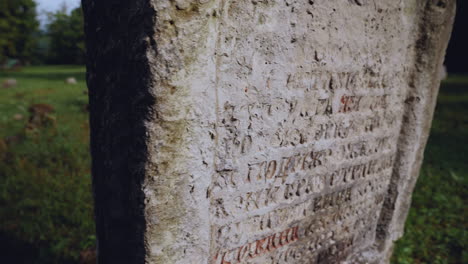 the most cinematic closeup panning view of a tombstone with notes of an old christian grave in the graveyard