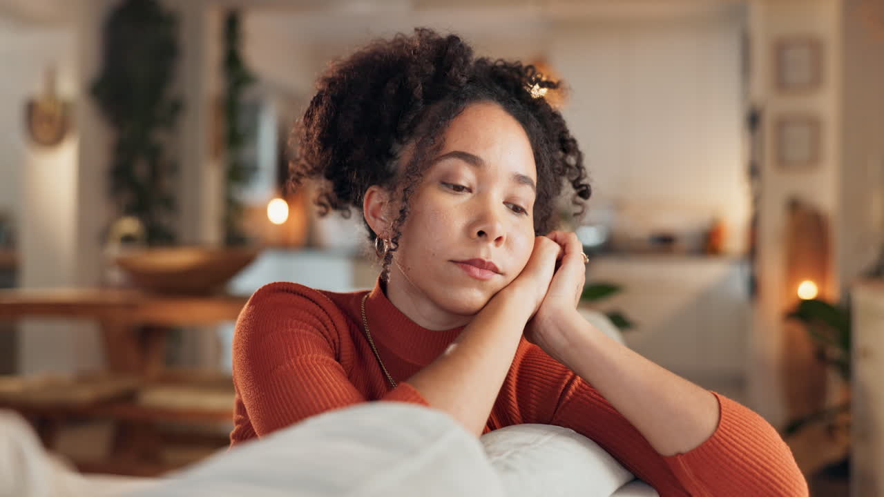 Woman looking sad and thoughtful on a sofa