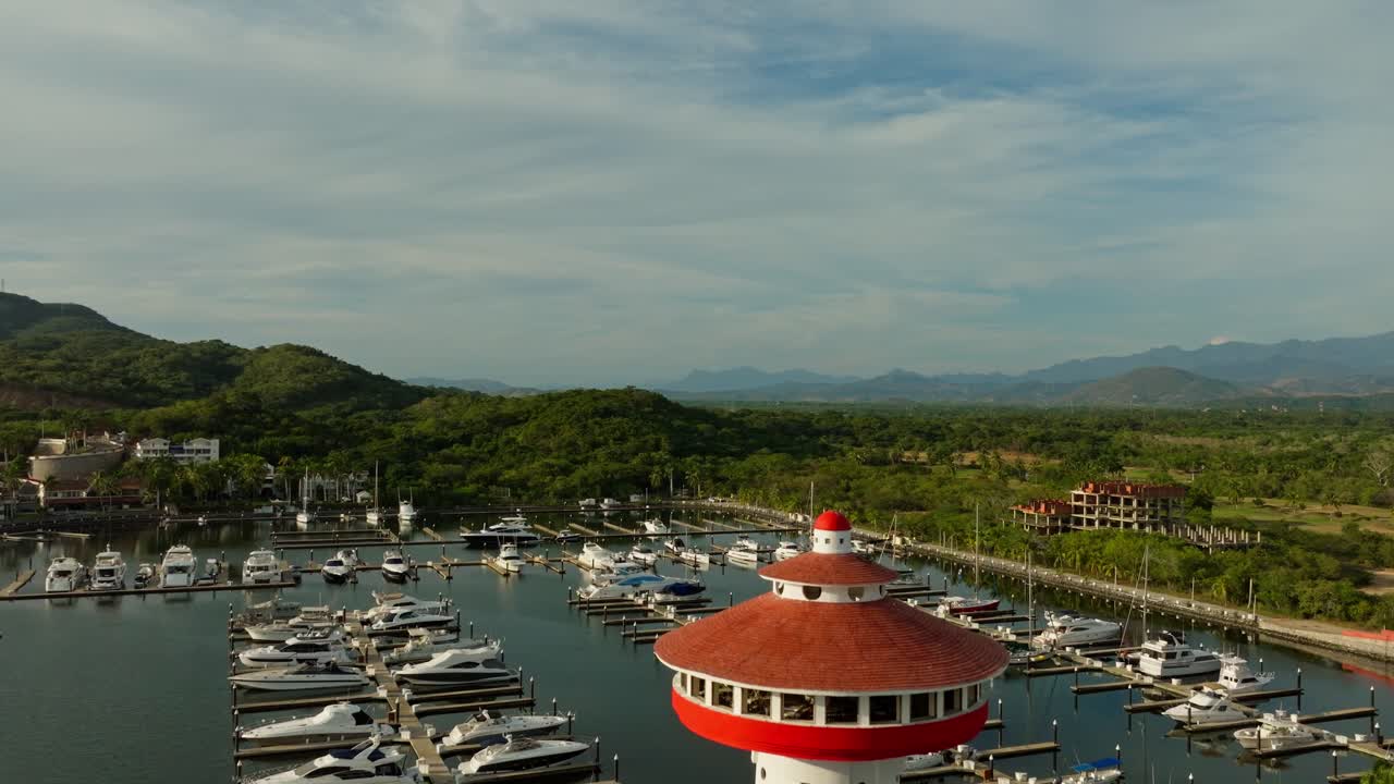 DRONE: CRANE LIKE SHOT OF THE LIGHT HOUSE AT THE MARINA IN IXTAPA, ZIHUATANEJO ( SUNSET )