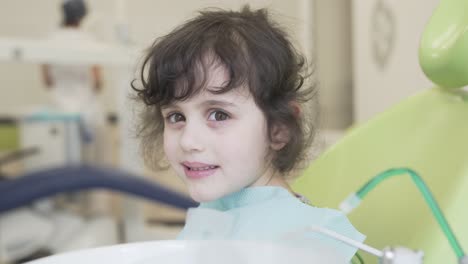 A-close-up-video-of-pretty-and-cute-little-brunette-girl-who-sits-in-the-chair-in-dentist-clinic