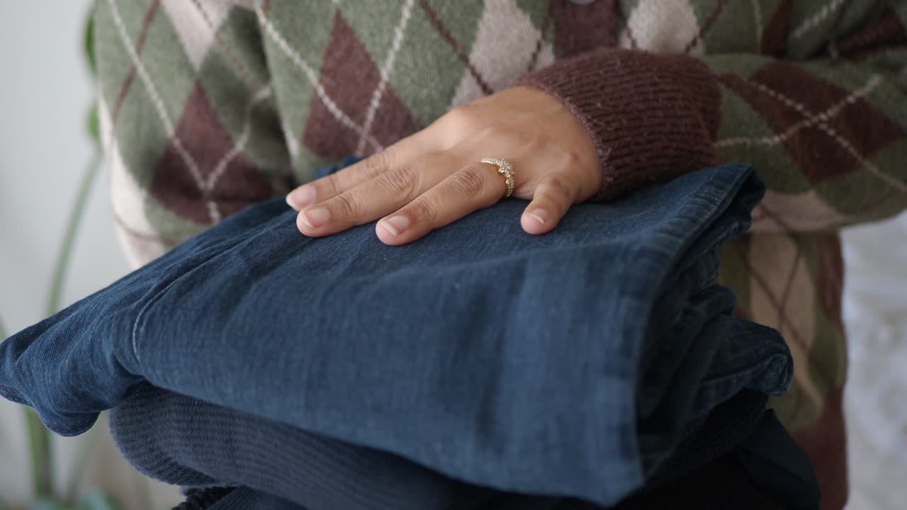 Close-up of Person Holding Stack of Folded Jeans