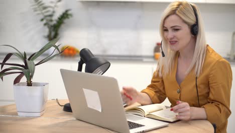 woman in headphones communicates by video call on a laptop