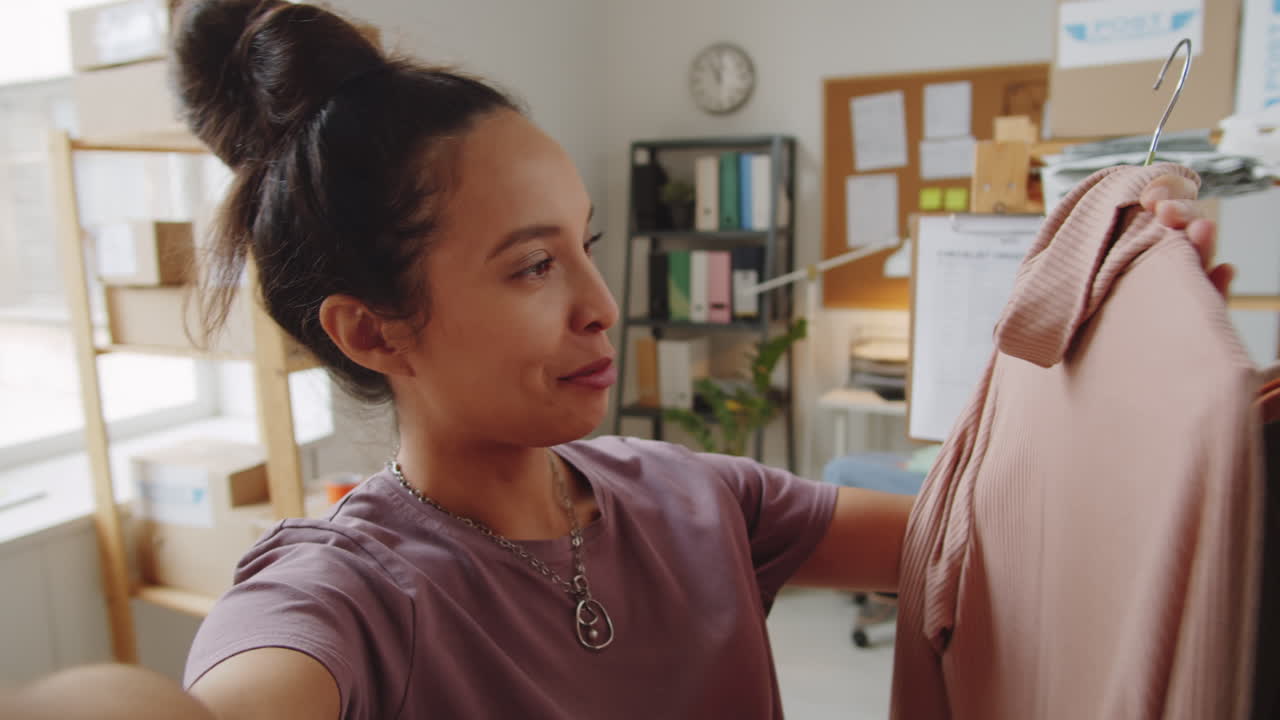 mujer mostrando un suéter nuevo en su oficina en casa