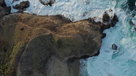 rocky shoreline birds eye aerial view with waves crashing into shore