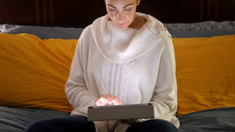 woman using digital tablet on bed