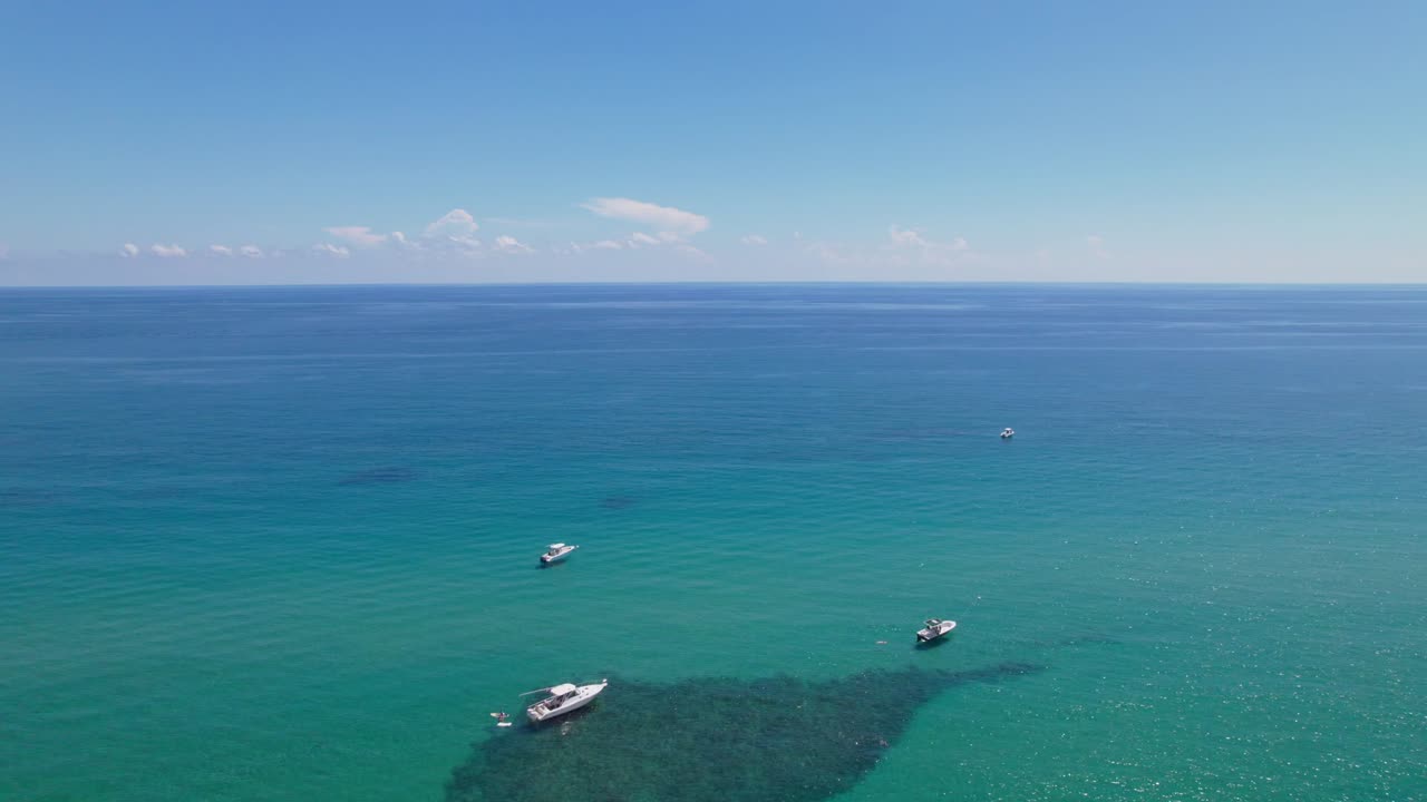 웨스트  ⁇  비치 스카이라인 다운타운 지역과 아름다운 해변 모래와 물 속의 보트를 지나가는 드론