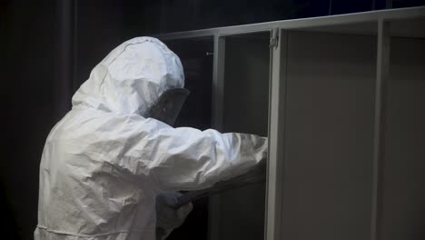 industrial worker in protective gear painting metal cabinet