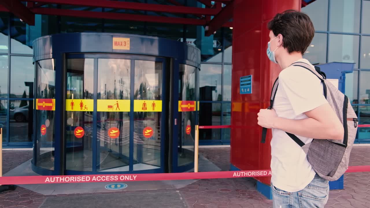 CHISINAU, MOLDOVA - JUNE 19, 2020: Man with a white t-shirt, backpack and surgical mask standing near the airport exit. Traveling during Corona Virus pandemic outbreak. Chisinau, Moldova