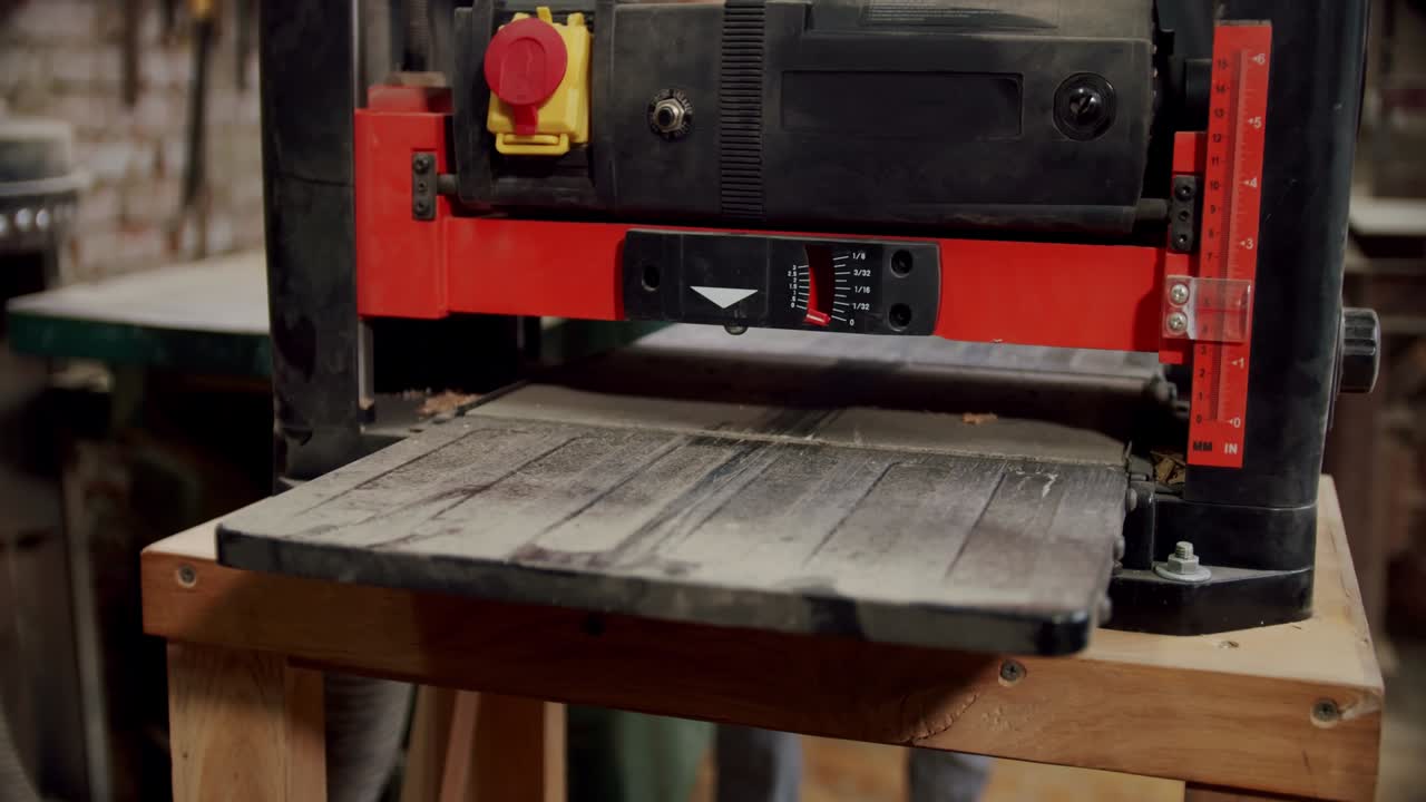 en un primer plano, el maestro enciende la máquina de carpintería e inserta una barra de madera en la máquina.