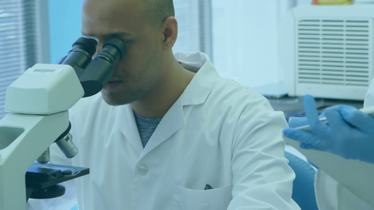 Purple hex overlay appearing, man at lab microscope pointing at it while tech confirming on tablet