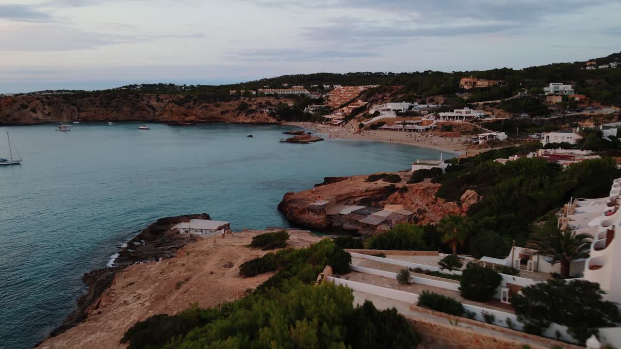 Aerial Dolly Over Coastline At Cala Tarida With Tilt Down View Of Small Bay In Late Afternoon