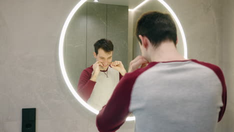 hombre limpiando los dientes con hilo dental en el baño