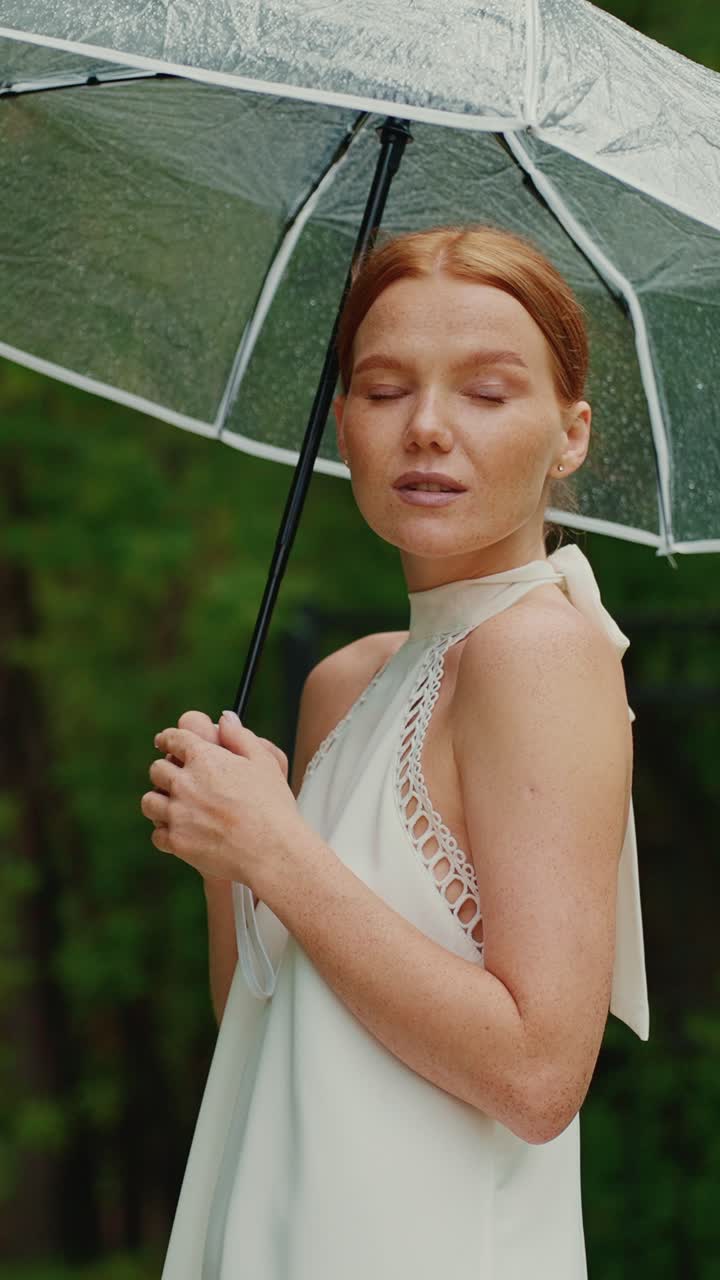 Woman in white dress with umbrella in the rain