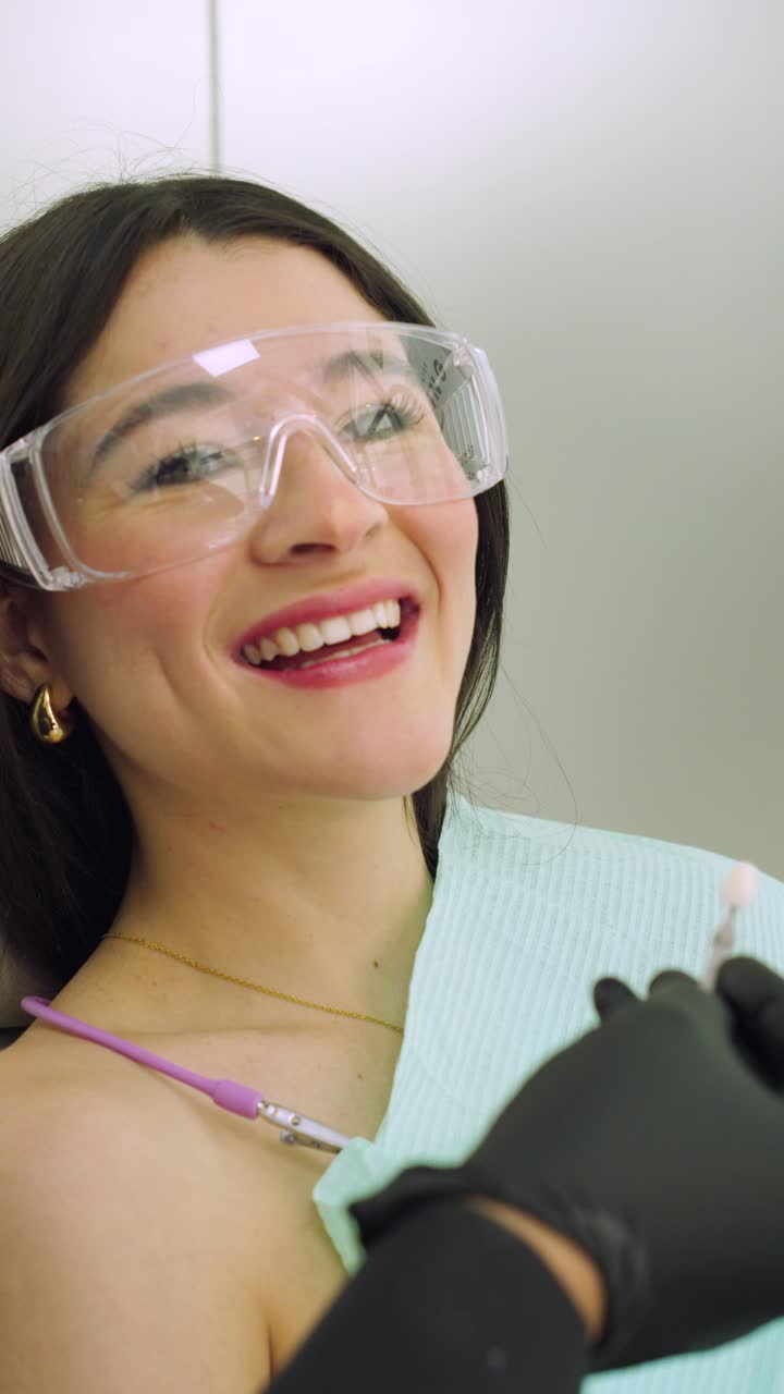 Giovane donna ispanica felice dal dentista per la scelta della tonalità dei denti, cura dentale