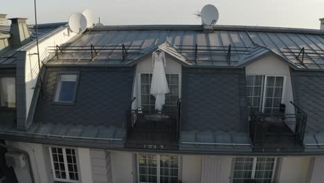 white wedding dress hangs on special hanger in doorway of balcony of luxury house, aerial view