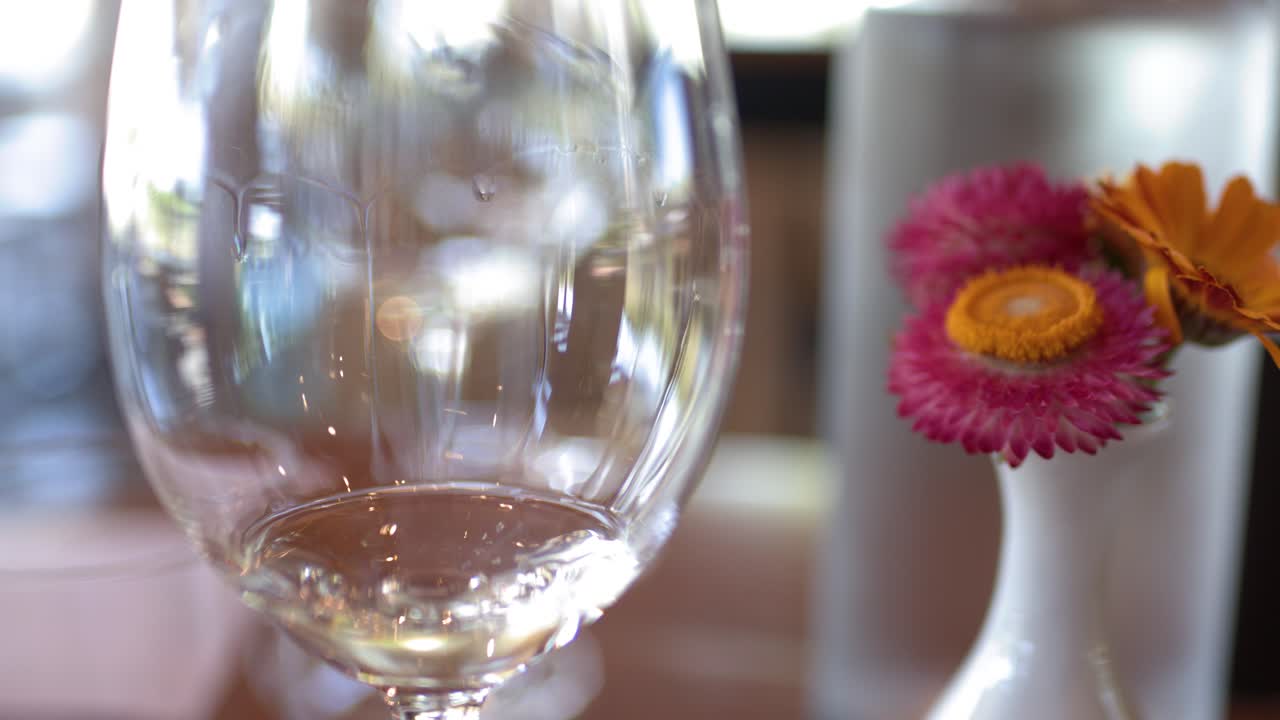 Nærbillede af et hvidvinsglas og blomster på et restaurantbord
