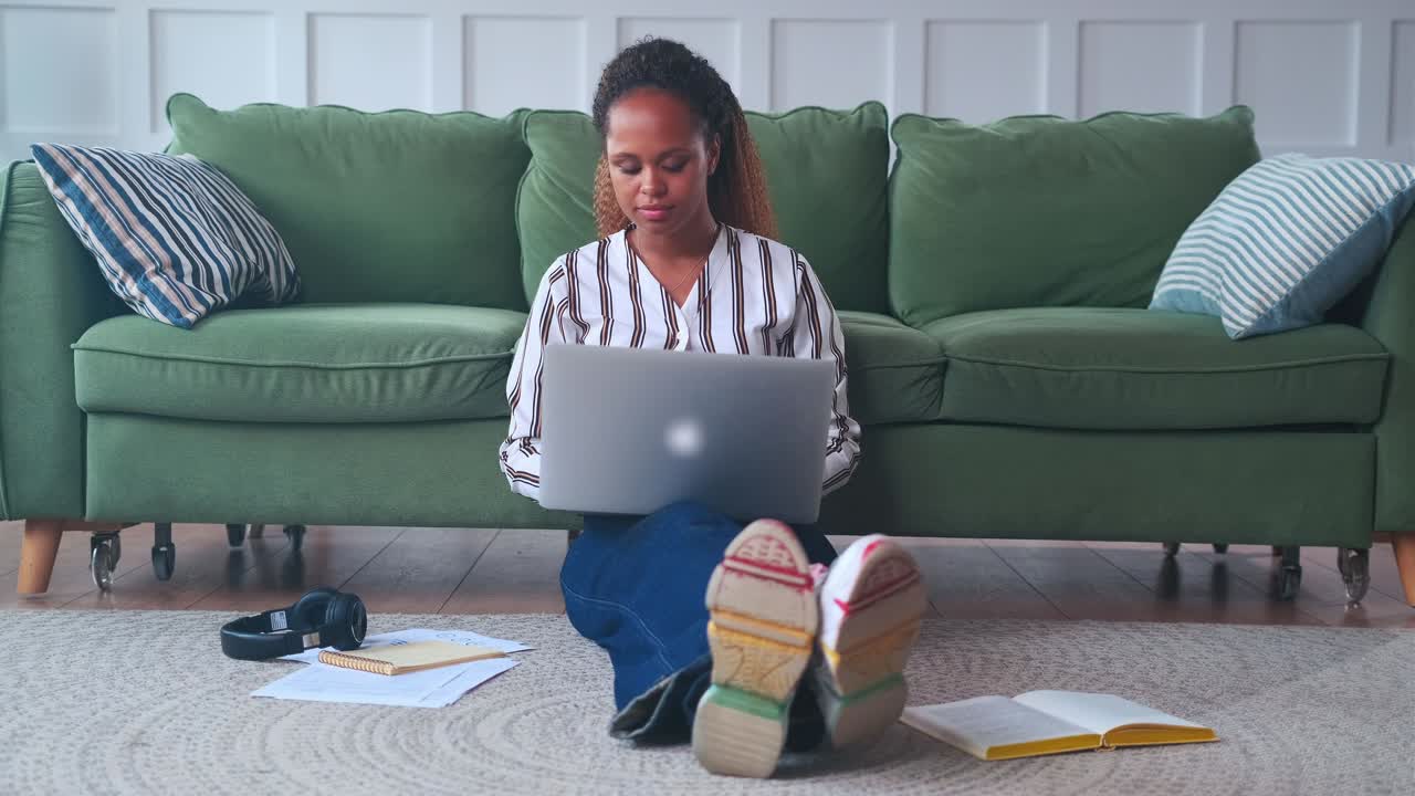 African american woman performs home work assigned at university using laptop
