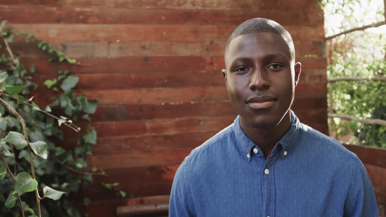 retrato de un feliz hombre afroamericano sonriendo en una terraza al aire libre, espacio de copia, cámara lenta.