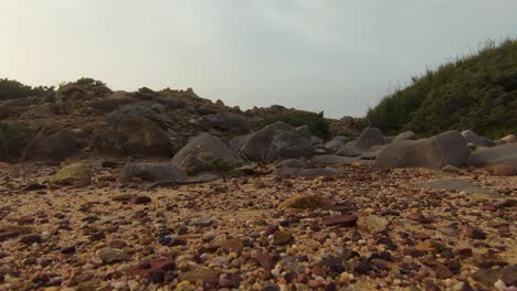 vista del suelo por un dron en movimiento hacia adelante de grandes piedras negras en arena marrón