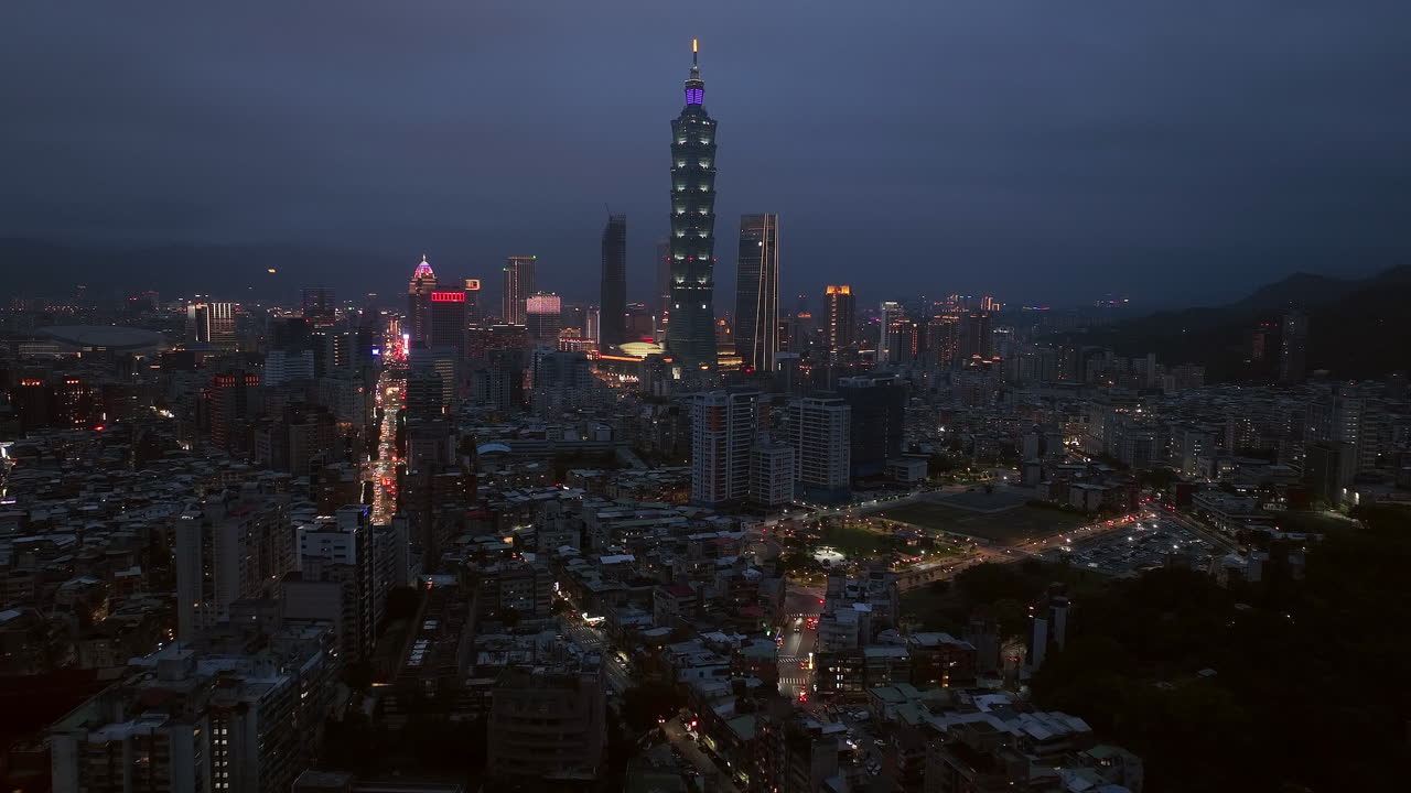 Sakte fremoverflyging mot Taipei 101-tårnet i Taipeis bybilde om natten