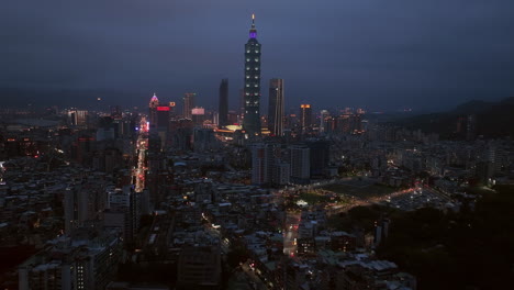 slow forward flight towards lighting 101 tower in cityscape of taipei at night