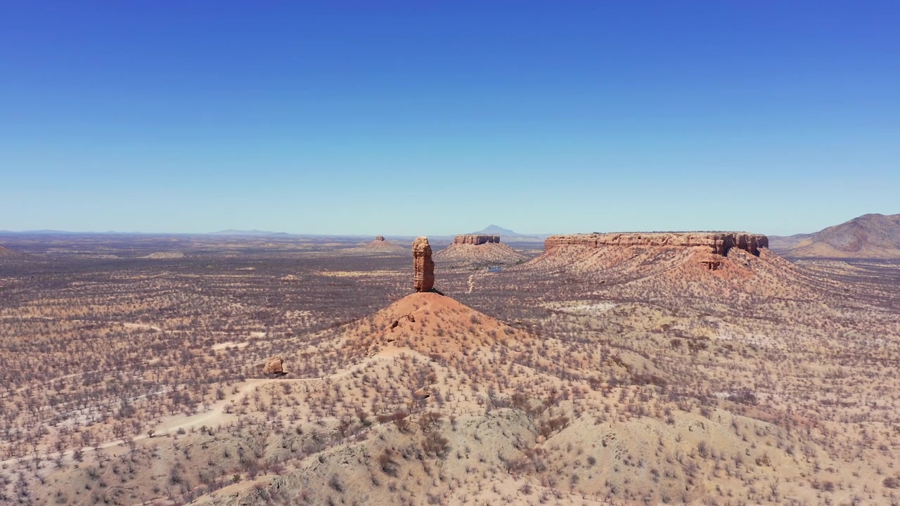 Ripresa aerea panoramica di Fingerklippe, Namibia a mezzogiorno. Iconica guglia rocciosa sopra un paesaggio arido. Alberi spogli, cielo limpido e senza nuvole