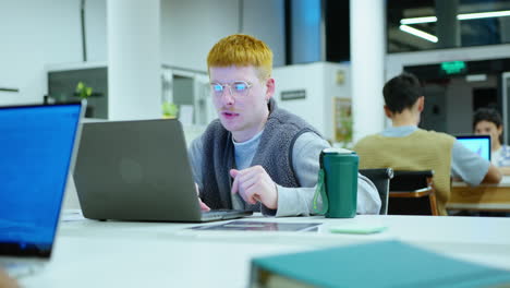 young male office worker using laptop at desk