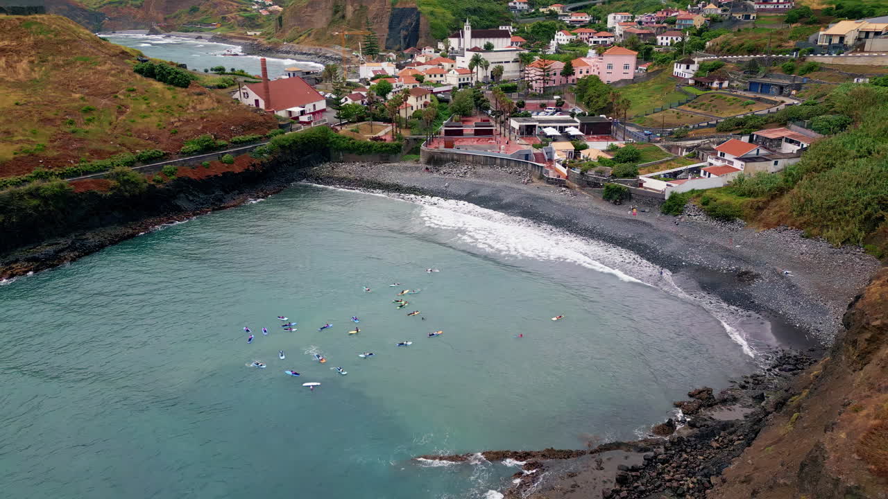 Kayak alla deriva nella baia in superficie. Onde che si infrangono sulla costa rocciosa. Città sulla riva