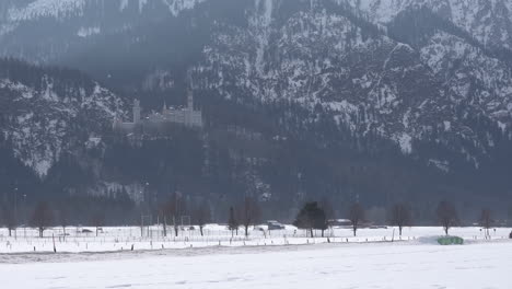 Schloss-Neuschwanstein-In-Der-Ferne,-Blick-Von-Einer-Straße-In-Schwangau,-Während-Autos-Vorbeifahren,-4K-Rohmaterial