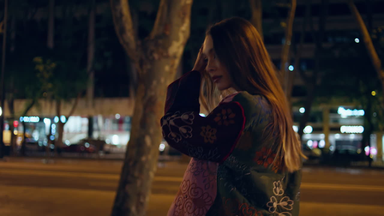 밤에 시내를 걸어다니는 여자, 카메라를 찾는 여자, 늦은 저녁에 도시를 산책하는 여자