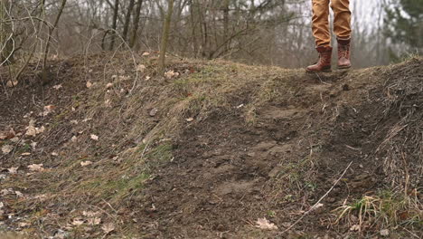 the boots of an unrecognizable person walking down a slope in the countryside