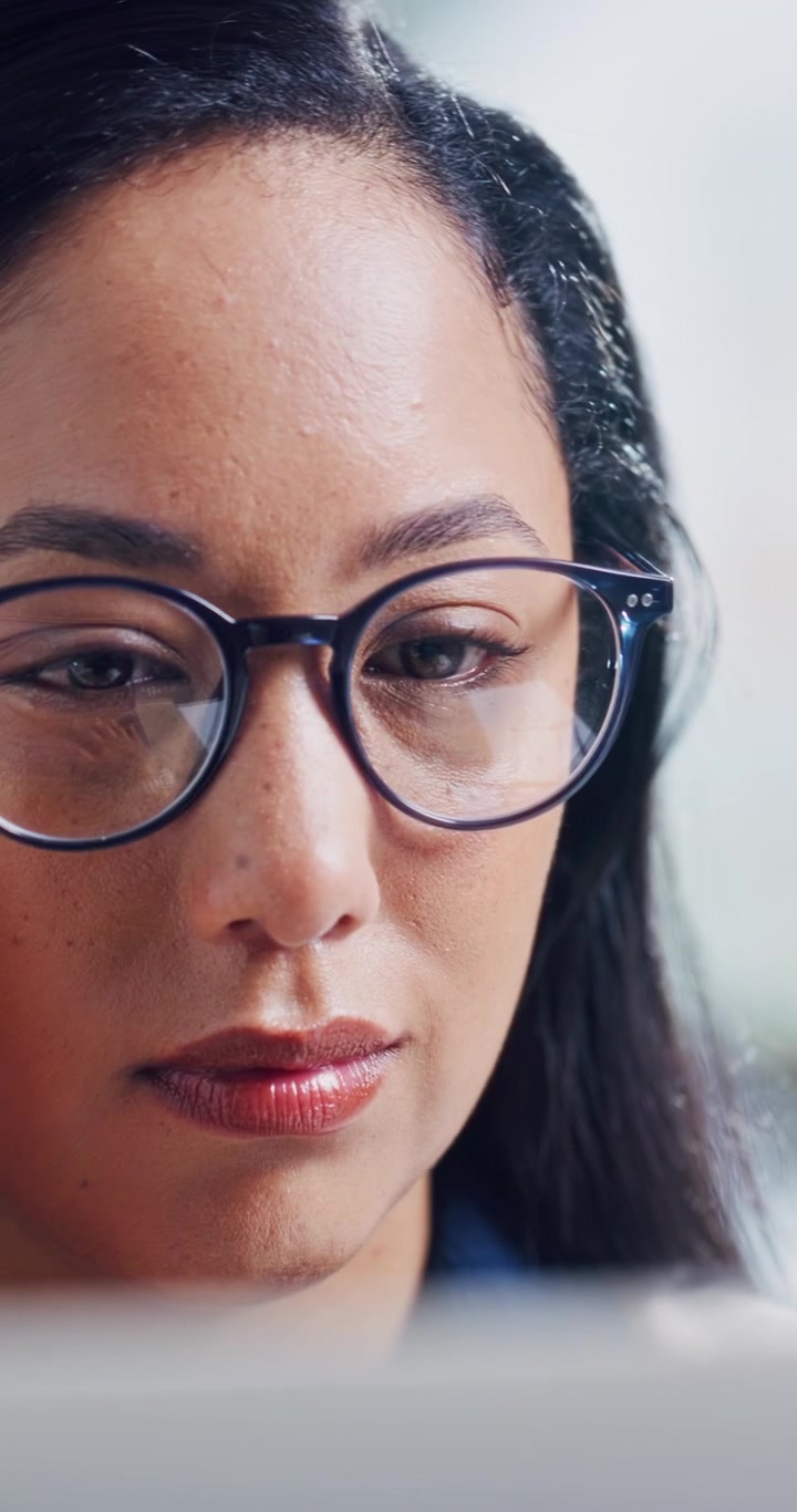Donna concentrata con gli occhiali che lavora al computer portatile