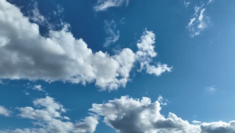 Fluffy white clouds float across a bright blue sky on a sunny day