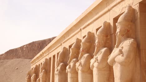 fila de estatuas de faraón mirando hacia el valle frente al templo de hatshepsut en luxor, egipto