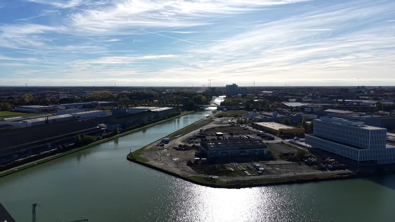 River with industrial factory and companies in German town at sunny day. Aerial rising wide shot. Modern warehouses in suburb of city. Autumn season