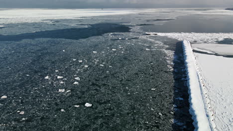 Rising-drone-shot-over-ice-covered-pier-on-Lake-Huron-in-Michigan