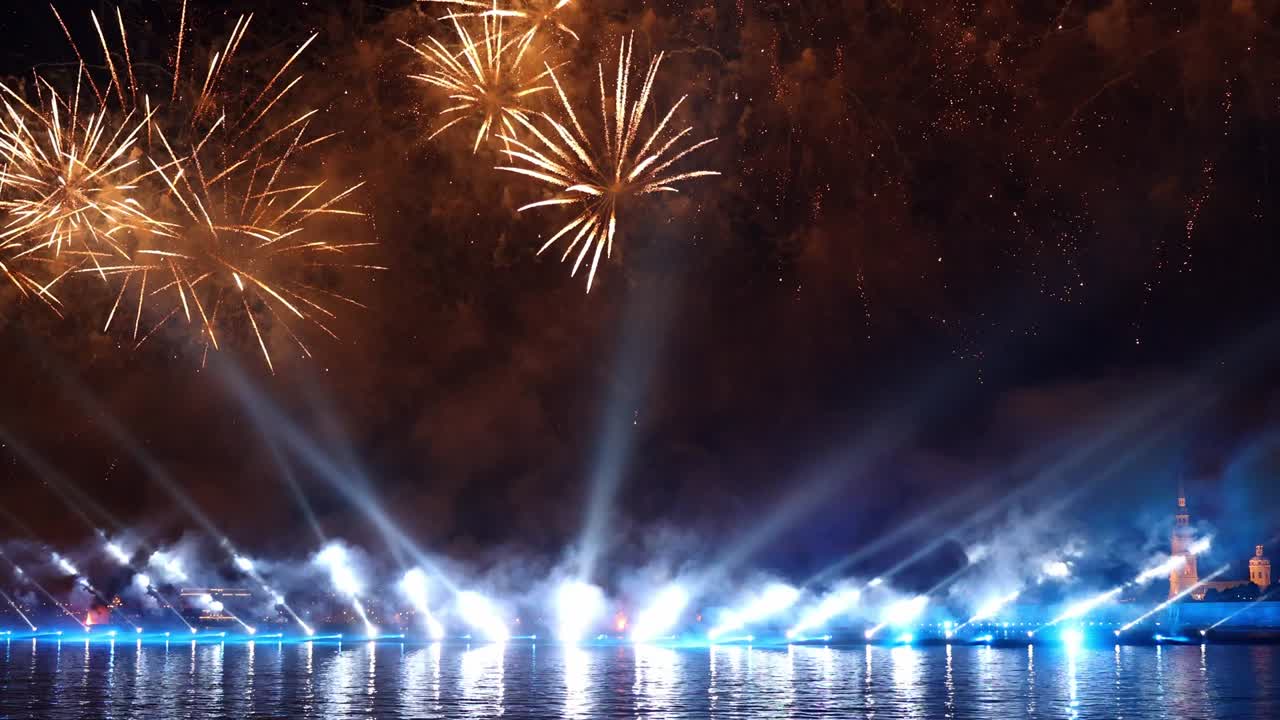 fuegos artificiales coloridos festivos e iluminación en el cielo oscuro con un hermoso reflejo en el agua. velas escarlata de vacaciones