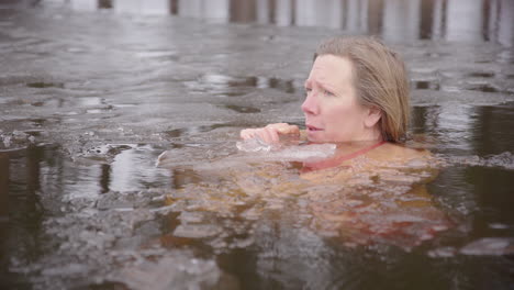 Caucasian-woman-takes-ice-bath-in-half-frozen-lake,-cold-water-therapy