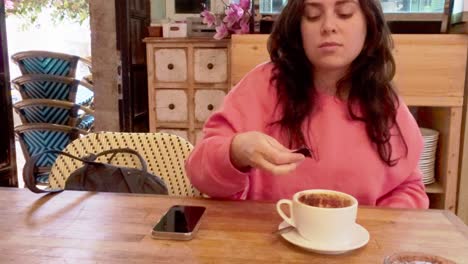 young woman adding sugar to cappuccino in cafe