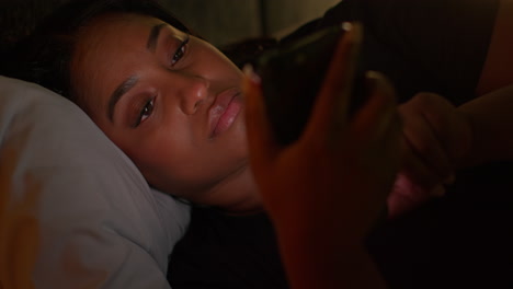 woman looking at phone in bed at night