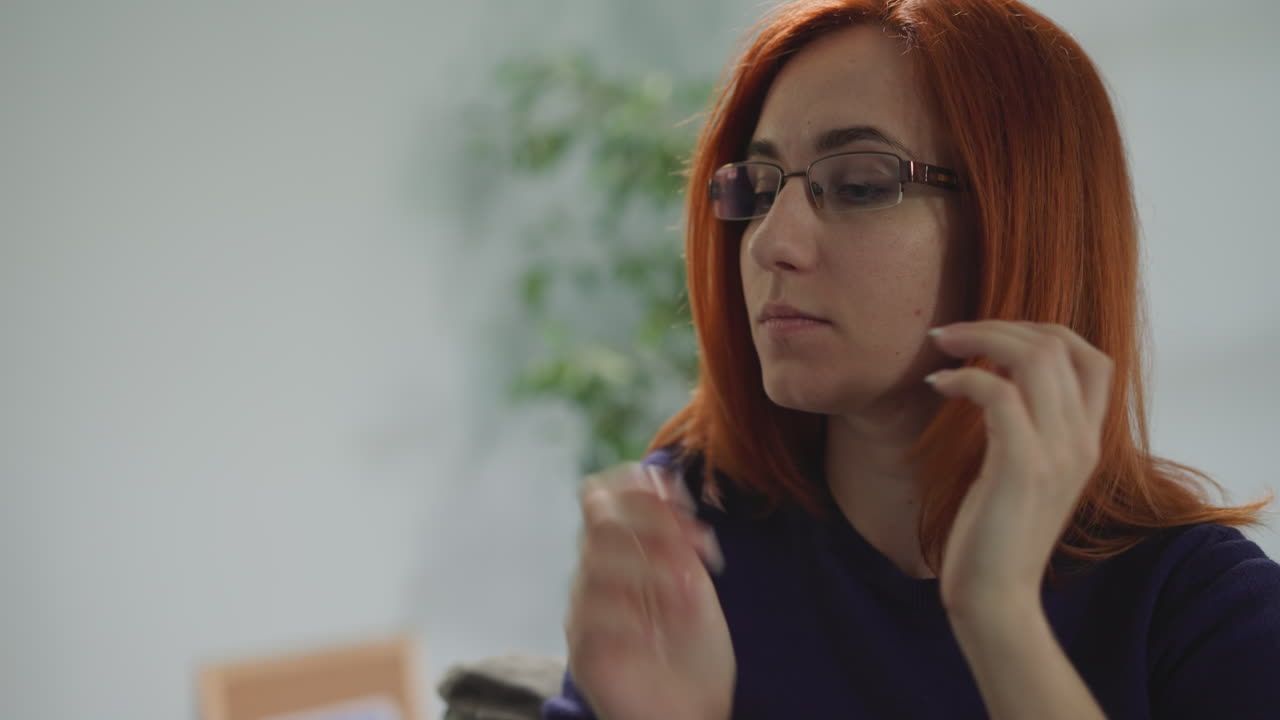 mujer con cabello rojo se pone gafas para continuar trabajando