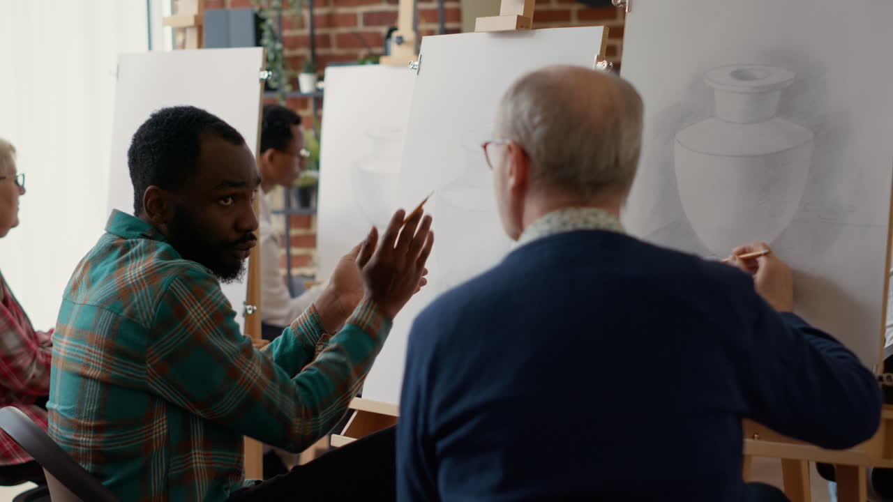 Team of art class students using pencil to draw vase design on canvas