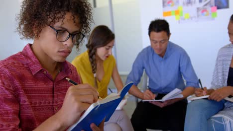 young mixed-race male executive writing on a diary in modern office 4k